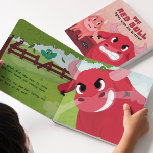 Boy holding an opened Red Bull storybook showing a furious Red Bull in a green fenced area and a green brid flying in the background. The cover of the Red Bull storybook appears behind.